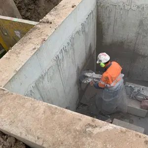 Worker cutting concrete inside a pit